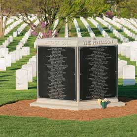 9-11 Memorial at Arlington National Cemetery shaped like a pentagon with names of victims engraved on plaques and rows of gravestones in the background