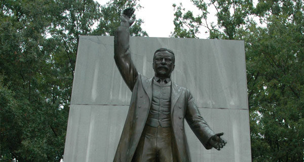 Statue of Theodore Roosevelt from the waist up and a large stone behind it