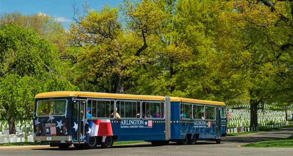 Arlington Cemetery Tours vehicle driving past large trees and rows of gravestones