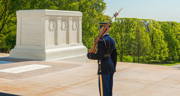 guard at tomb of unknown soldier standing watch in front of a large tomb above ground