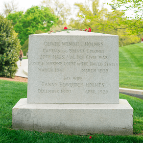 Head stone of Oliver Wendell Holmes sitting on a grassy field with part of road in the background