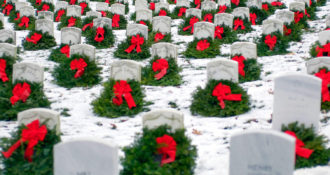 holiday wreaths across Arlington national cemetery gravestones with snow covering the ground